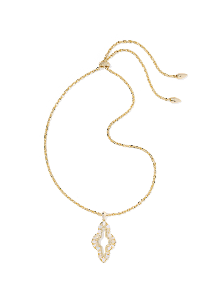 Gold necklace with a neutral stone colored pendant on a white background