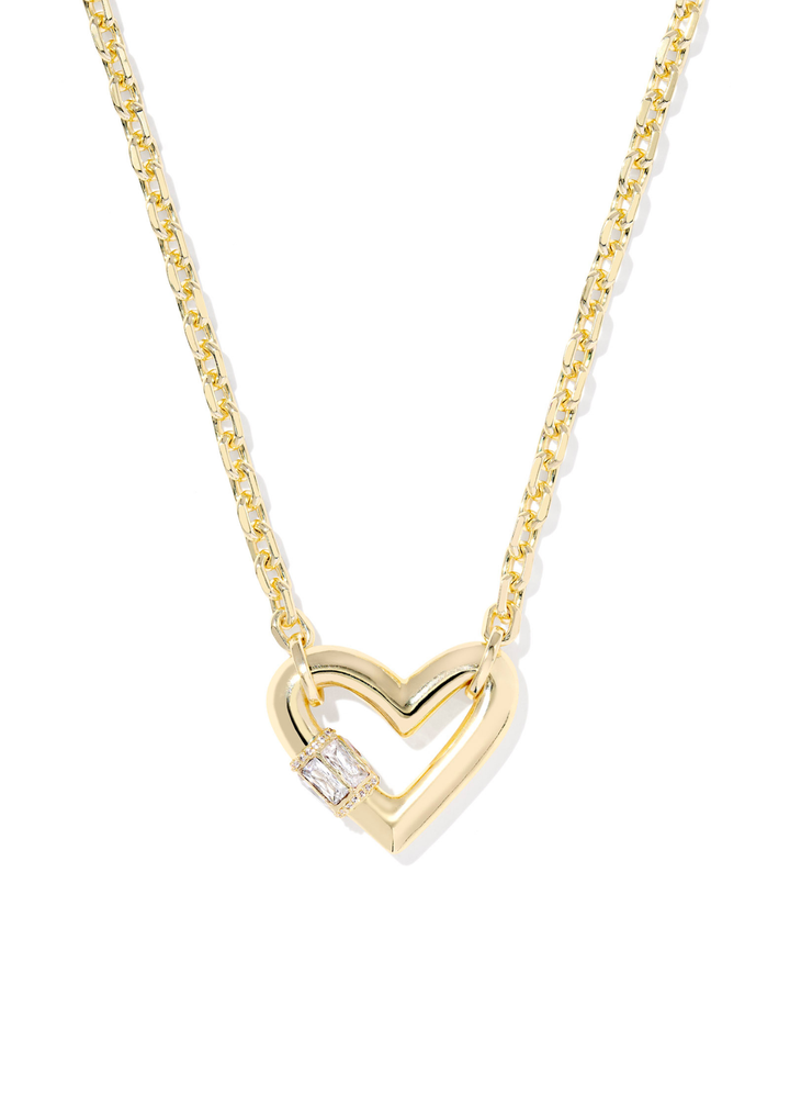 Gold necklace with a heart shaped pendant laying on a white background