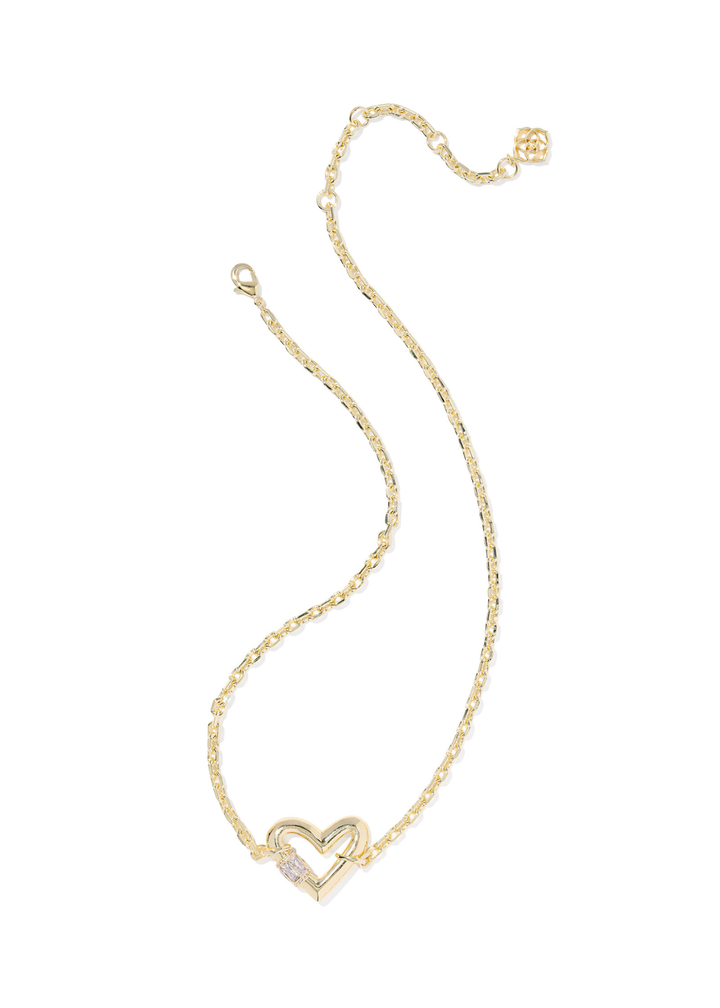 Gold necklace with a heart pendant laying on a white background