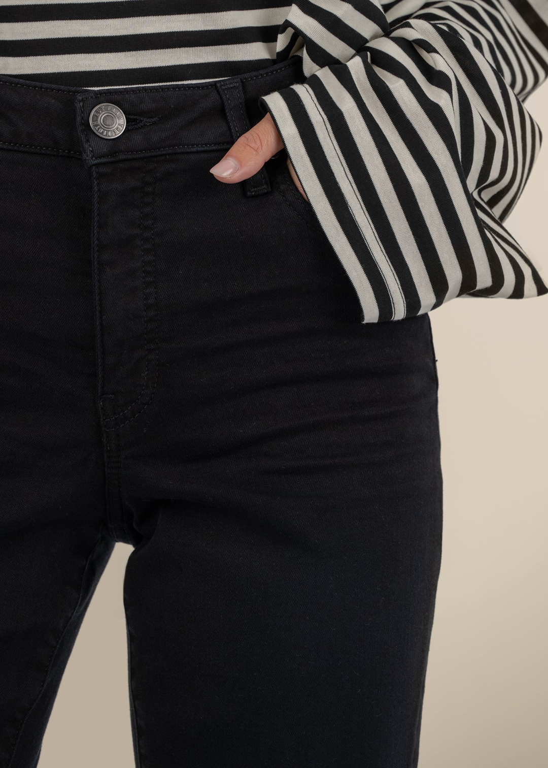 Close up of black jeans and a hand in the pocket.