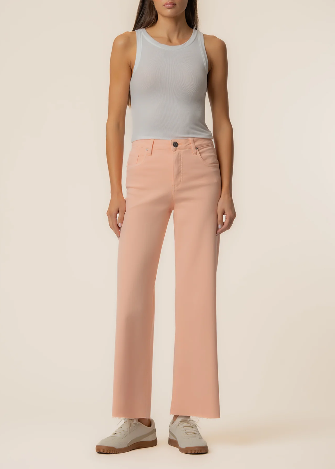 Woman wearing orange wide leg jeans with a grey tank and sneakers