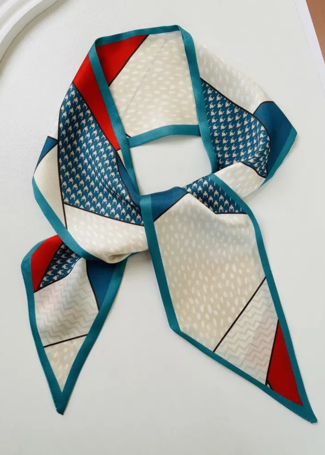 Red, white, and blue patterned satin scarf on a white background