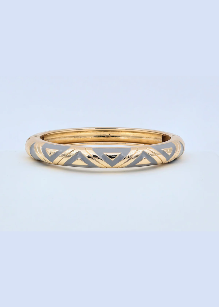 Gold and grey geometric pattern bangle bracelet on a blue background