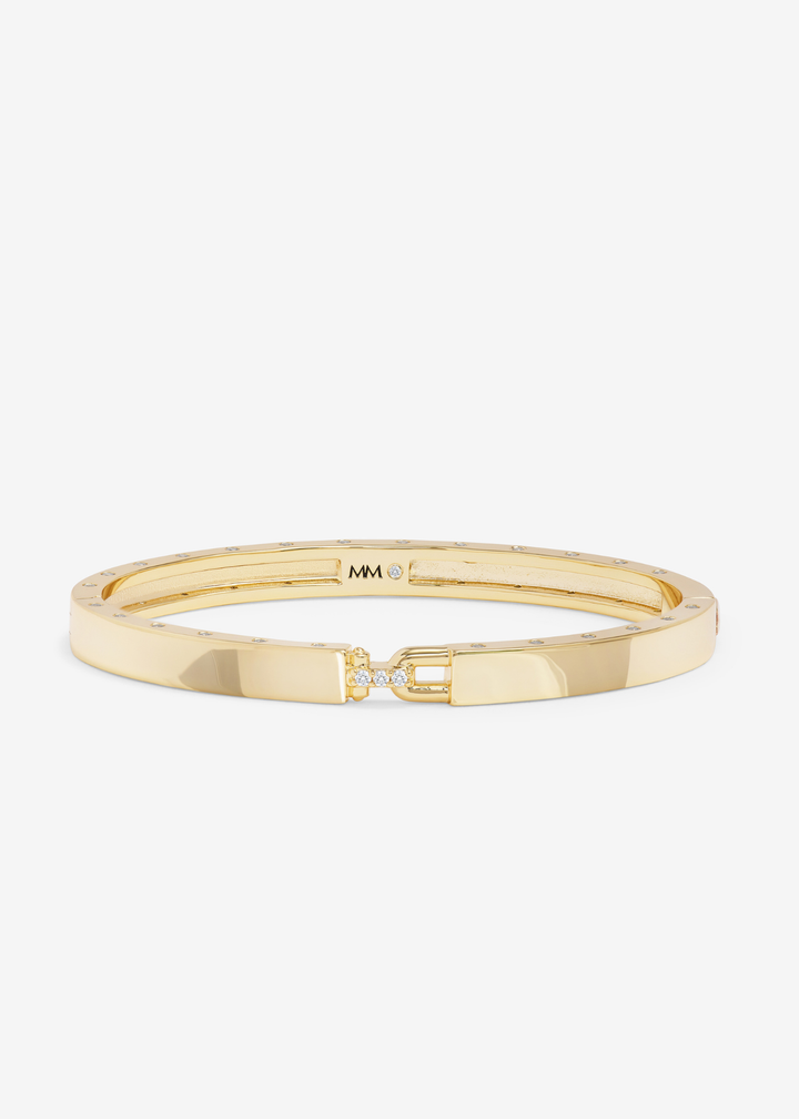 Gold cuff bracelet with a lock clasp on a white background