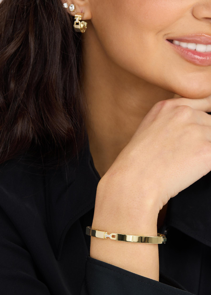 Woman wearing a gold cuff bracelet with a lock clasp 