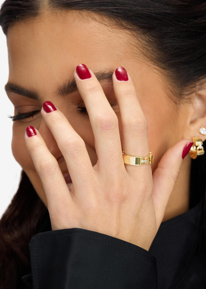 Woman wearing a gold band ring with CZ studding and a lock clasp