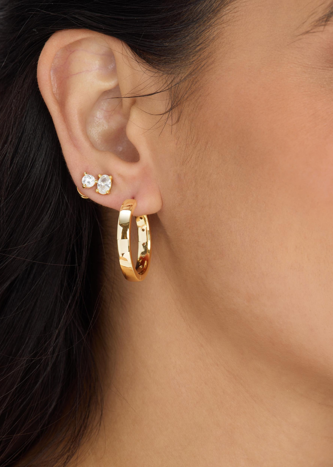 Woman wearing diamond studs with a gold hoop earring