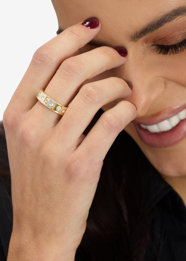 Woman wearing a gold band ring with CZ studs on a white background