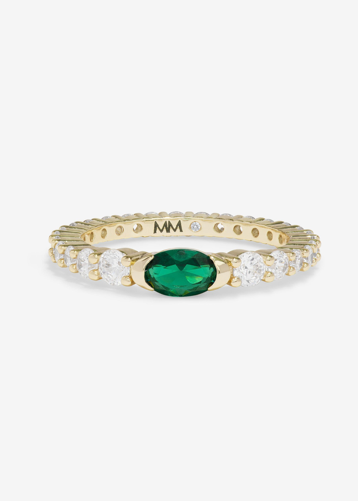 Gold ring with simulated diamonds and an emerald stone on a white background