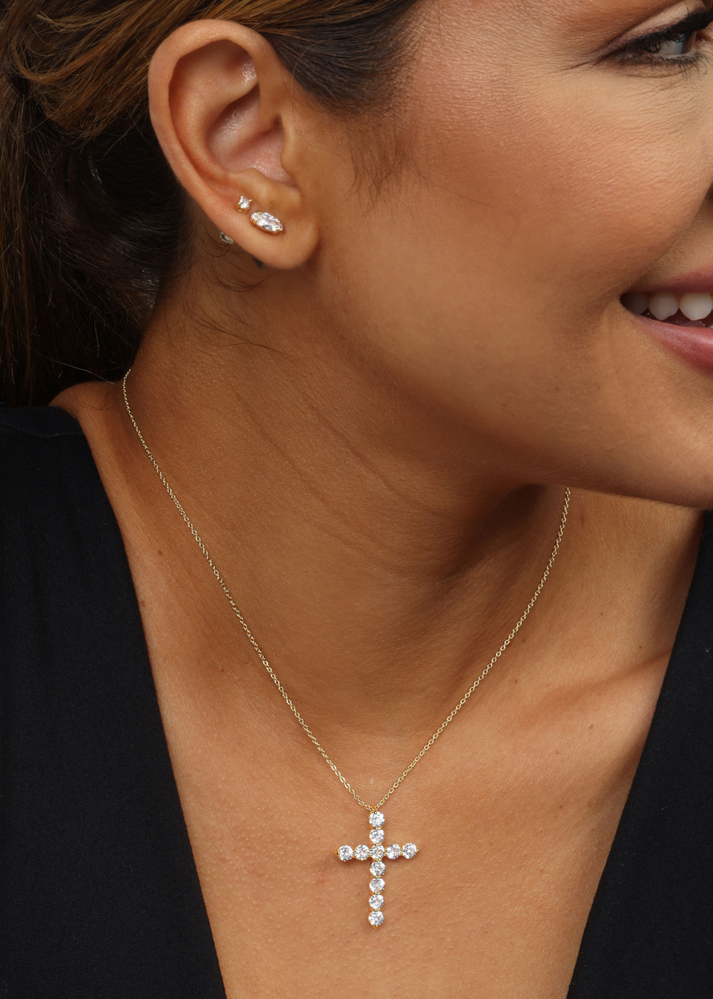 Woman wearing a gold necklace with a cross pendant with simulated diamonds