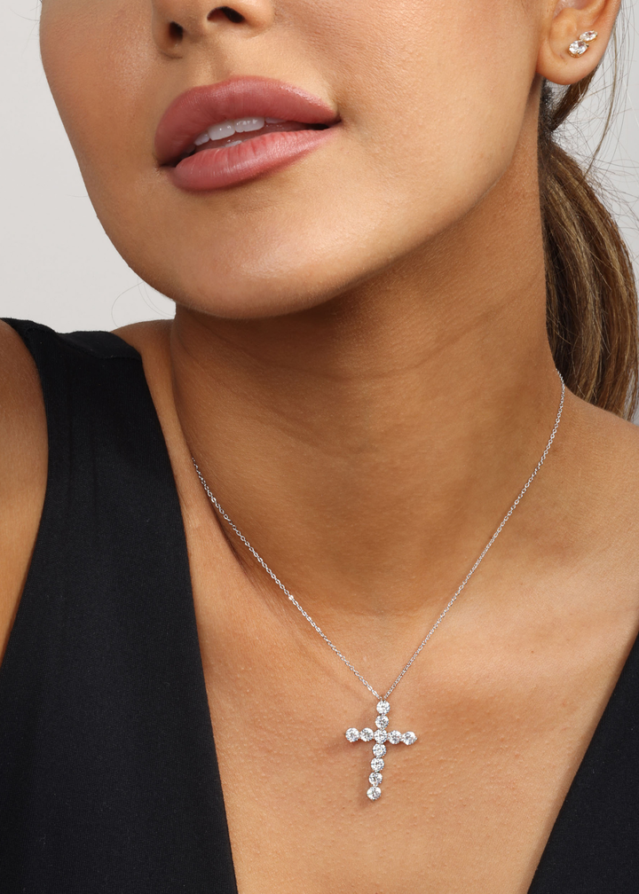 Woman wearing a silver cross necklace with simulated diamonds