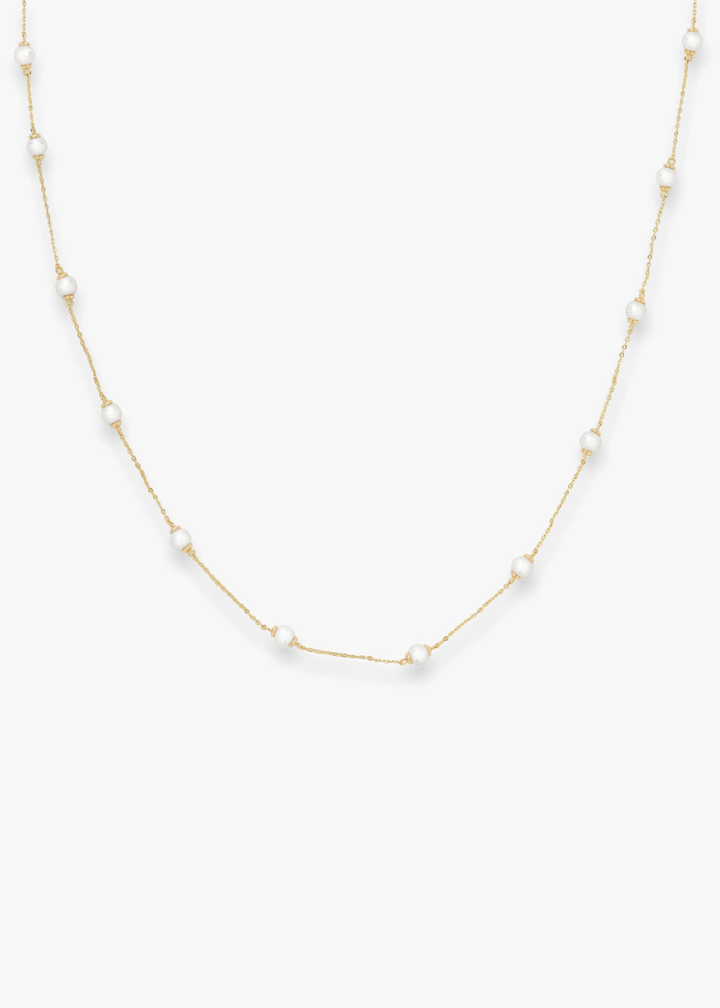 Gold pearl strand necklace on a white background