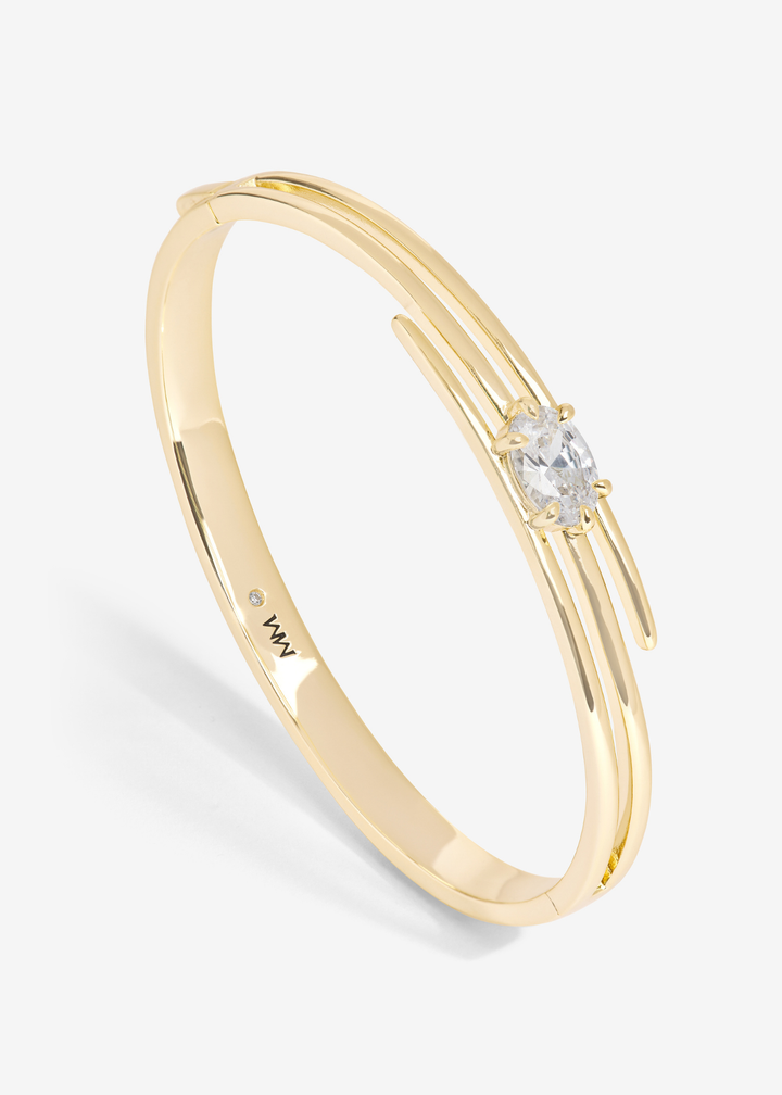 Gold lasso cuff bracelet with a diamond stud against a white background