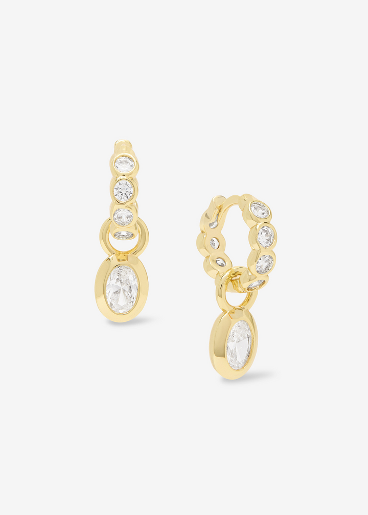 Gold huggie earrings with CZ's framed in gold on a white background