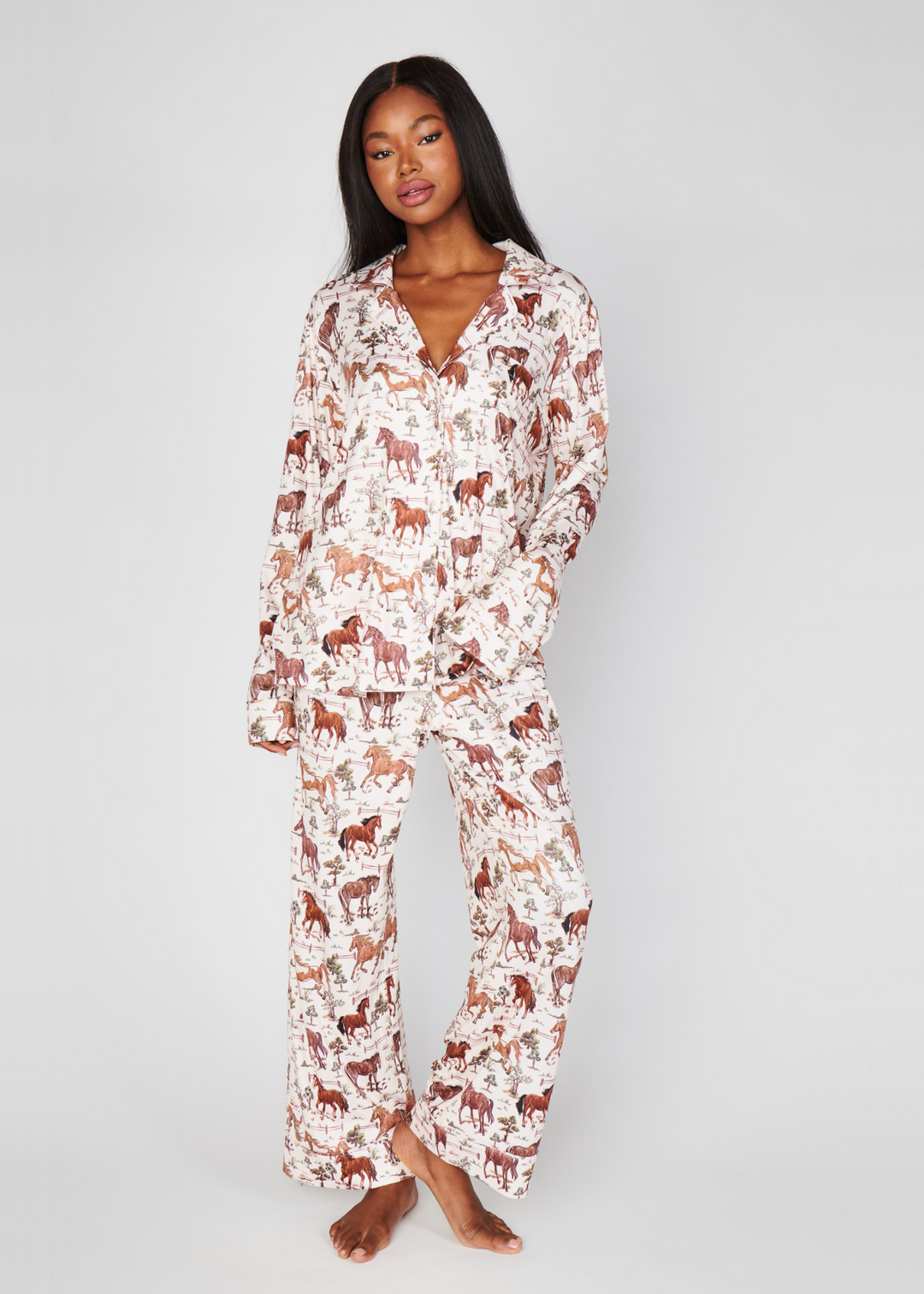 Woman wearing a white, long sleeve pajama set with a wild horses pattern