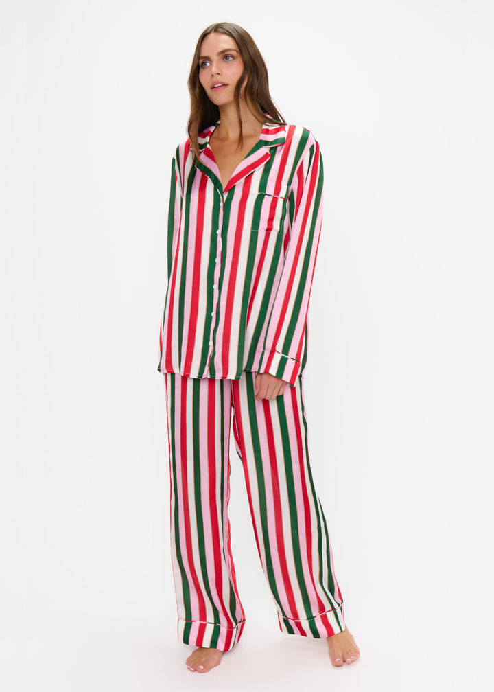 Woman wearing a matching pj set with red, green, pink, and white stripes against a white background
