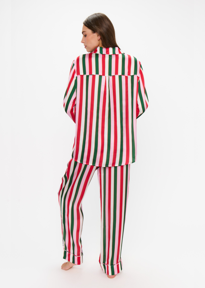 Woman turned around wearing a matching pj set with red, green, pink, and white stripes against a white background