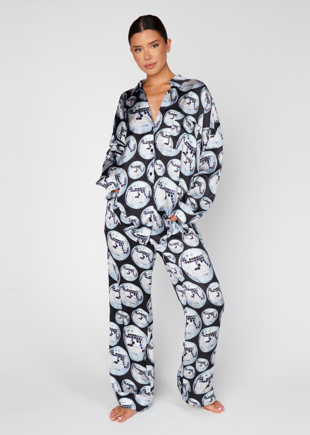 Woman wearing a black, grey, and white pajama set with a large disco ball print