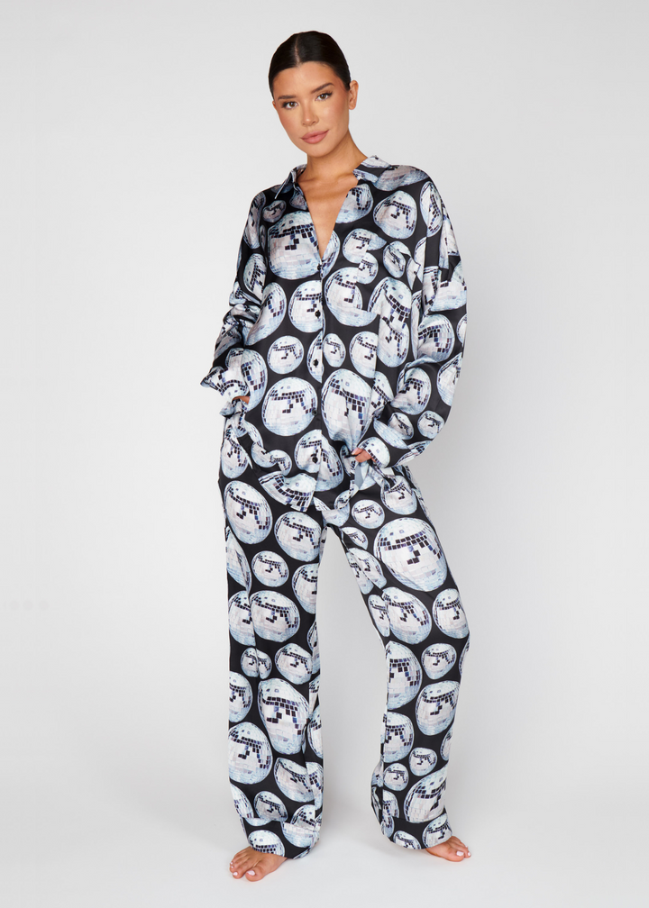 Woman wearing a black, grey, and white pajama set with a large disco ball print