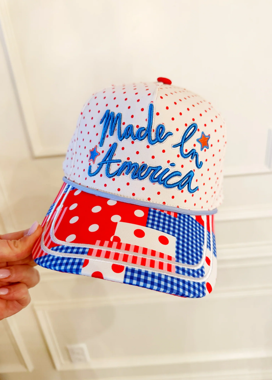 Hand holding a patterned trucker hat with a "Made In America" graphic