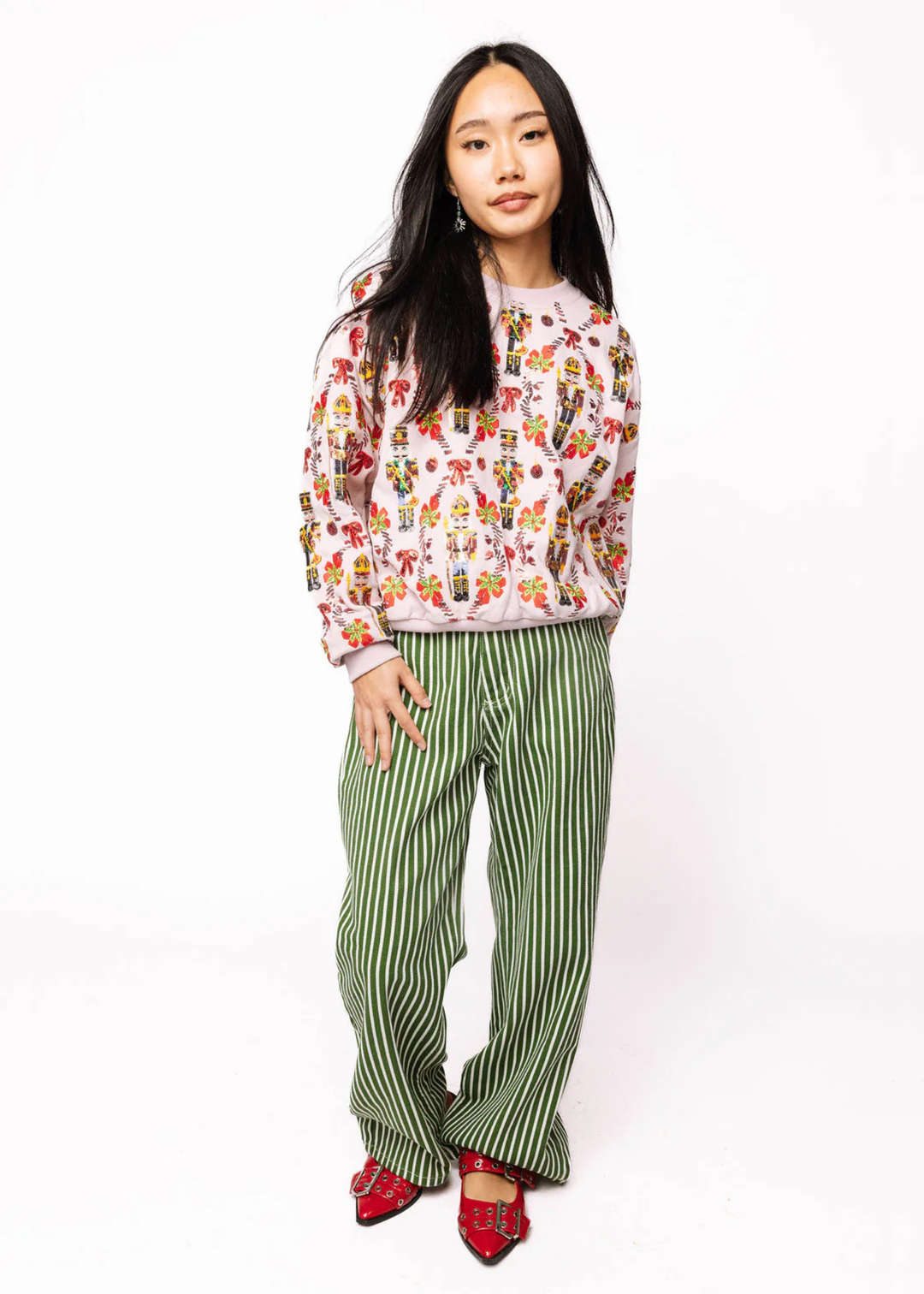 Woman wearing a sweatshirt with a nutcracker and candy cane sequin graphic
