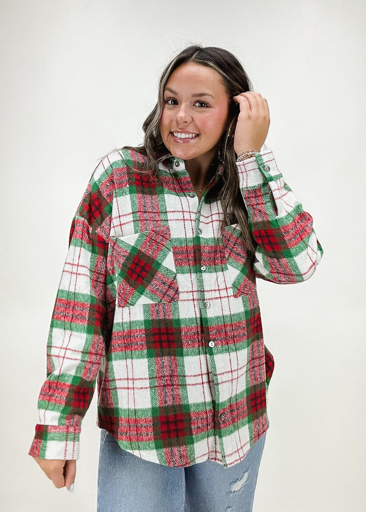 A woman wearing a red, green, and white plaid button-up shirt, styled with distressed jeans for a casual and festive look.