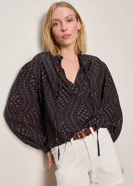 Woman wearing a black and brown patterned blouse with white shorts