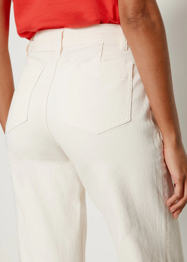 Close up of a woman turned around wearing very light pink jeans and a red t-shirt