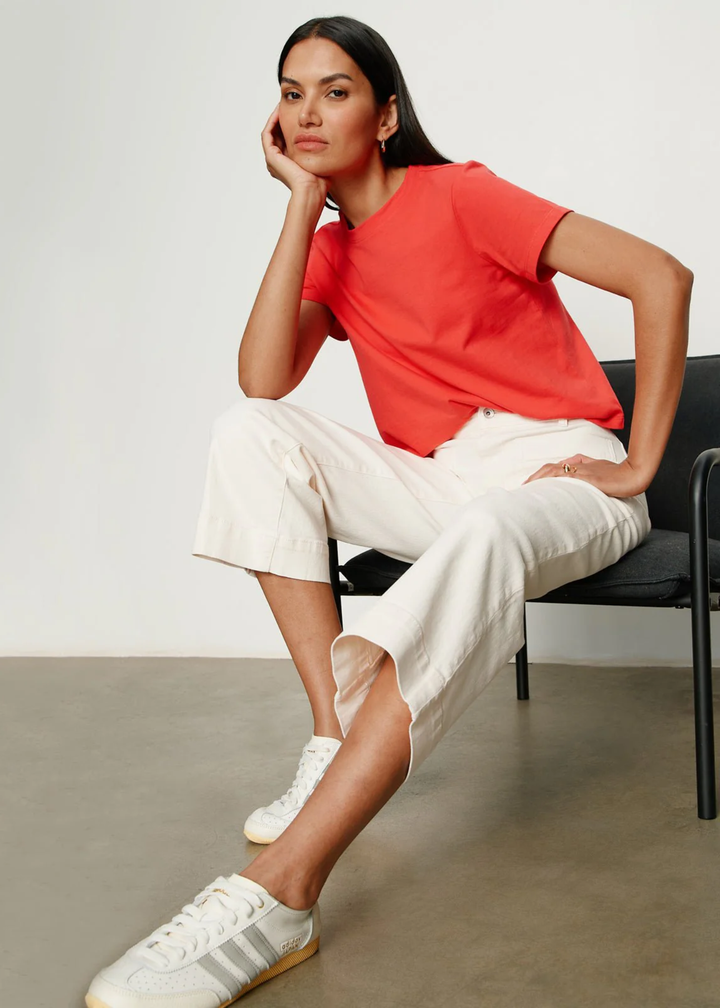 Woman sitting wearing a very light pink jean with a red t-shirt