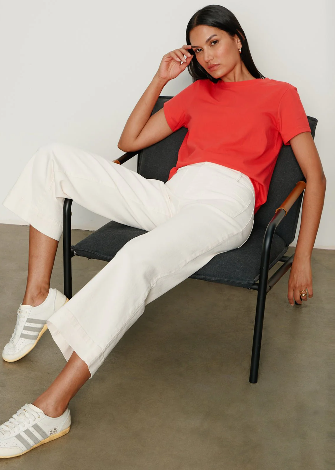 Woman sitting wearing a very light pink jean with a red t-shirt
