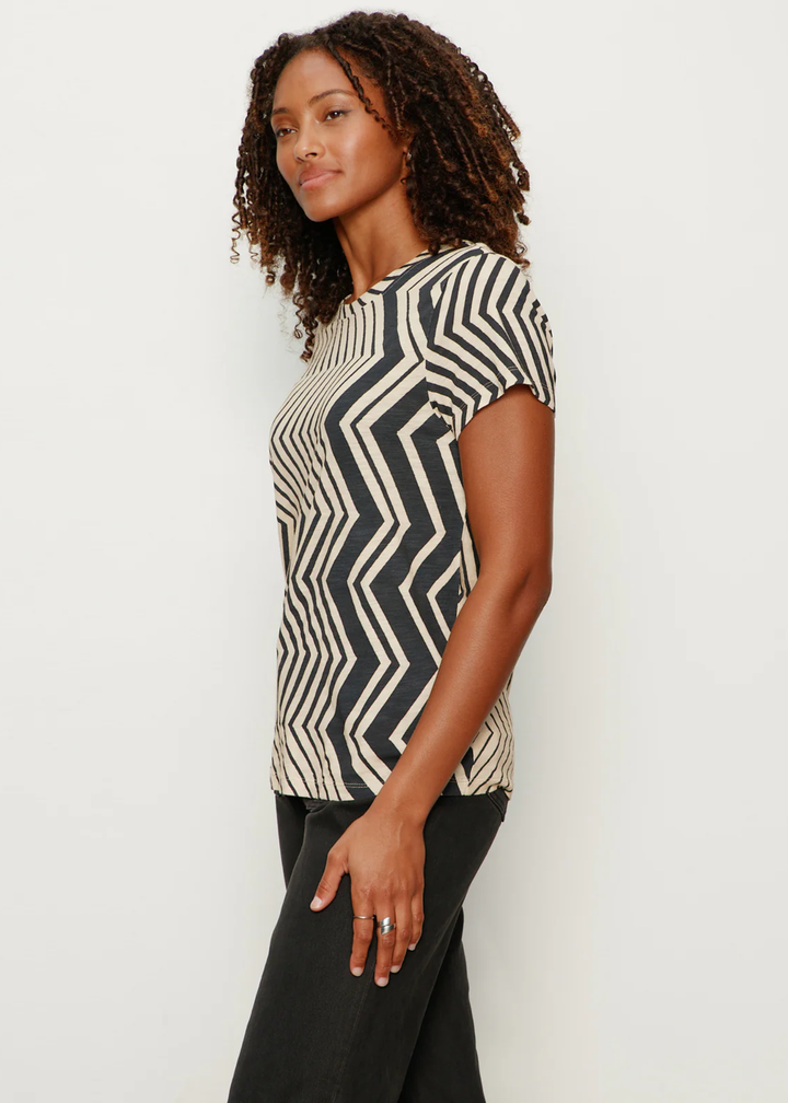 Woman turned to the side wearing a t-shirt with white and black zig zag stripes with black jeans