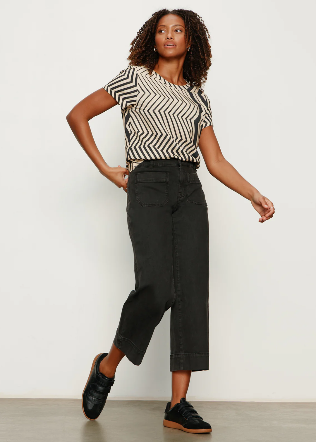 Woman wearing a t-shirt with white and black zig zag stripes with black jeans