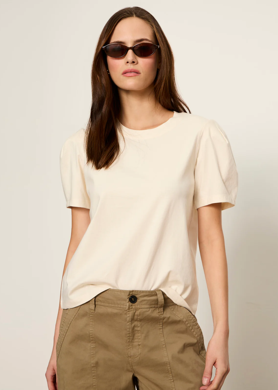 Woman wearing a cream top with tan pants and sunglasses