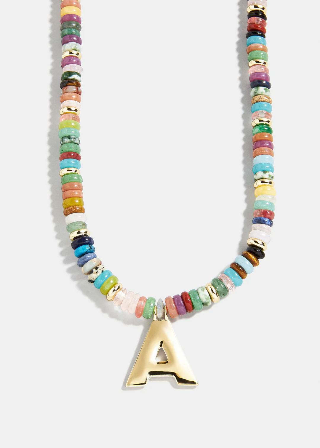 Multi color necklace with a gold black letter "A" charm laying on a grey background