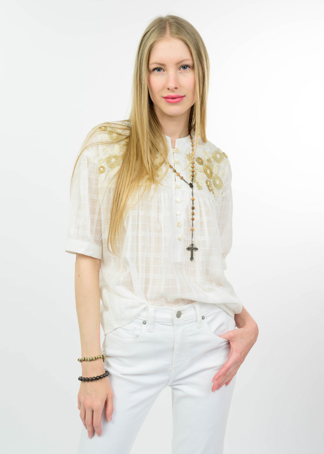 Woman wearing a white top with floral embroidery on the top and white jeans