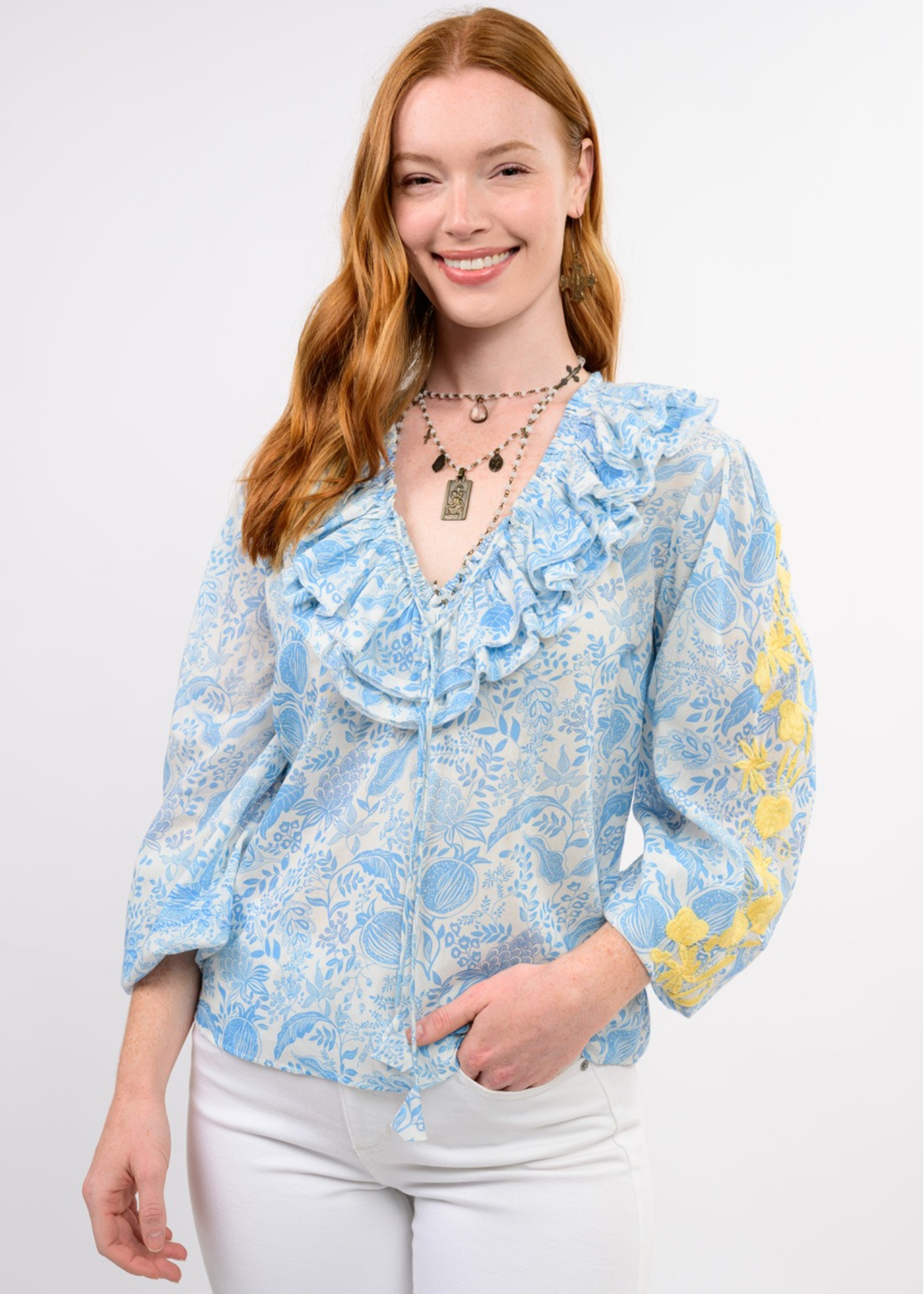 Woman wearing a blue floral top with yellow embroidery on the sleeves