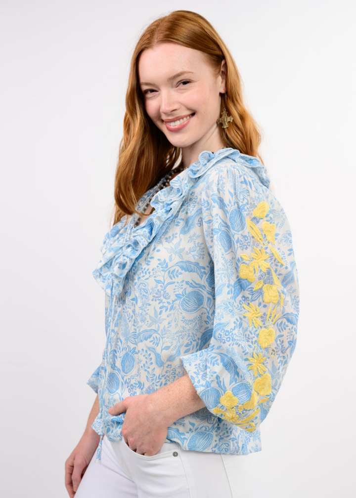 Woman wearing a blue floral top with yellow embroidery on the sleeves