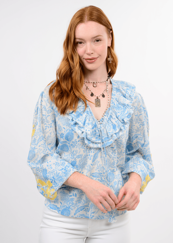 Woman wearing a blue floral top with yellow embroidery on the sleeves