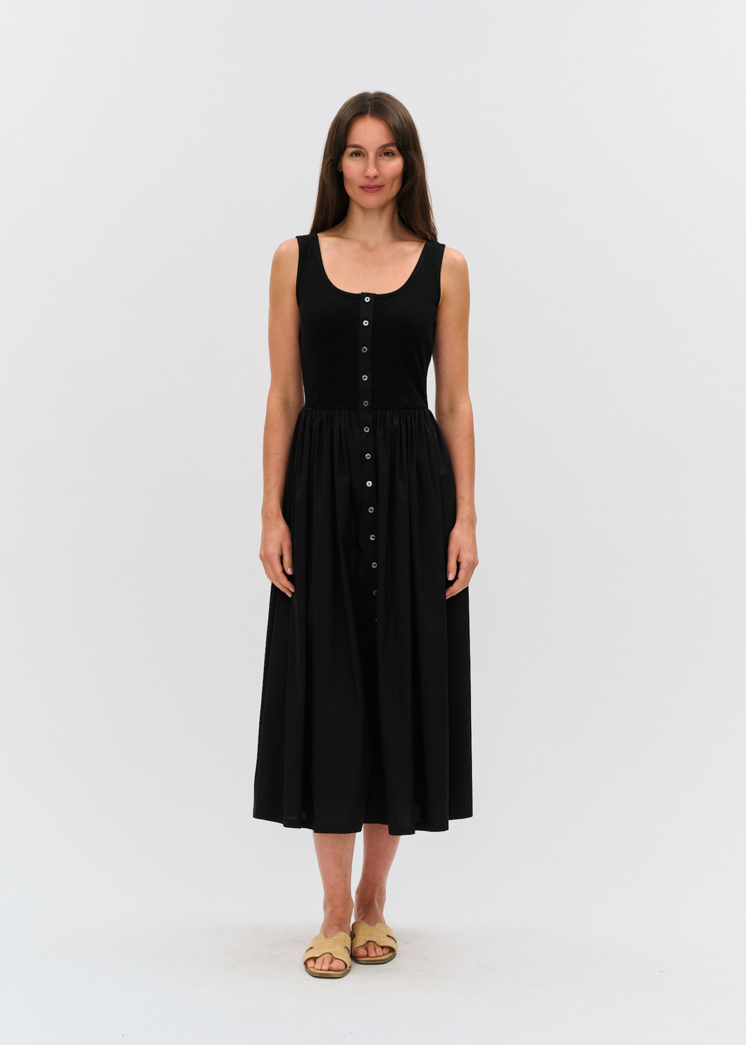 Woman wearing a black midi dress with tan sandals