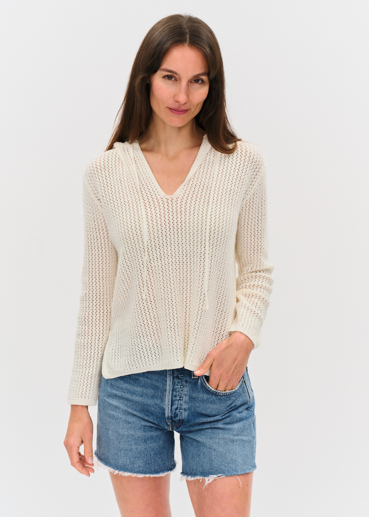 Woman wearing an ivory crochet hoodie with denim shorts