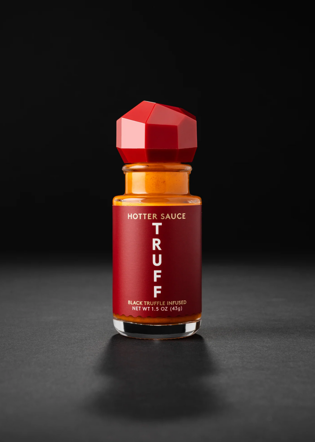 Mini TRUFF Hotter Sauce in a red bottle on  a black background