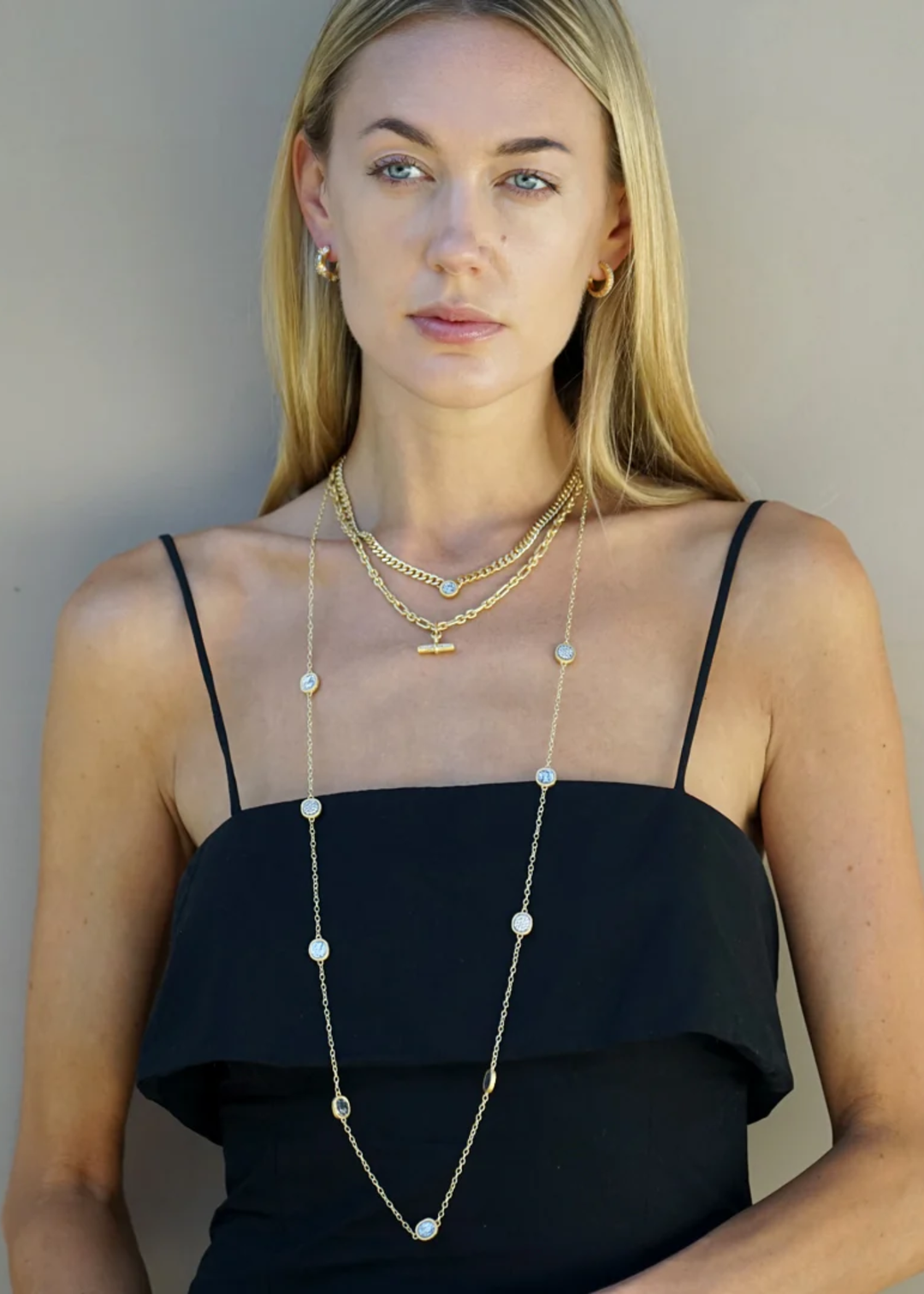 Woman wearing gold necklaces including a gold chain necklace with silver coins