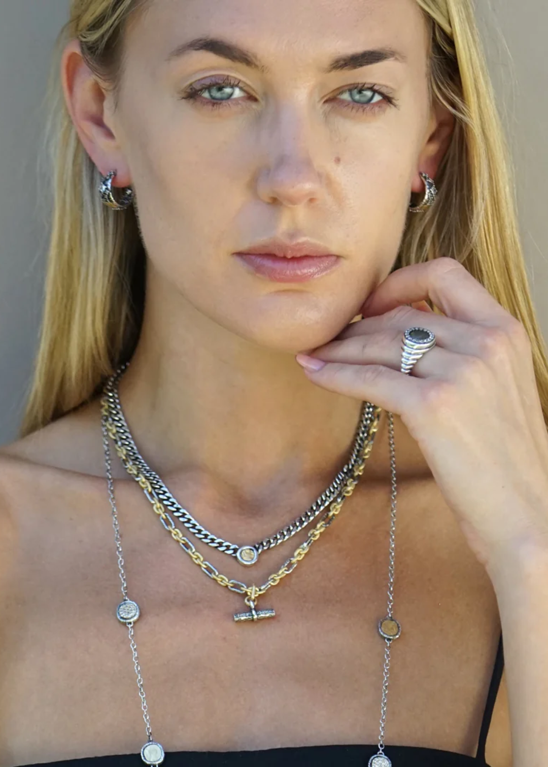 Woman wearing multiple layered necklaces with a mixed metal chain necklace with a CZ studded toggle