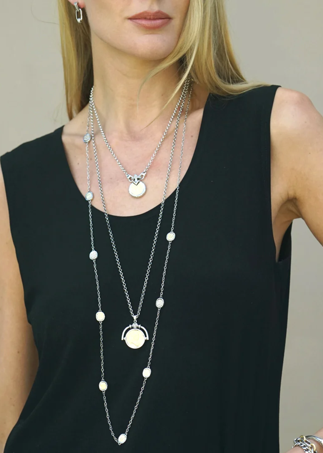 Woman wearing a vintage silver chain necklace with a gold coin and other necklaces