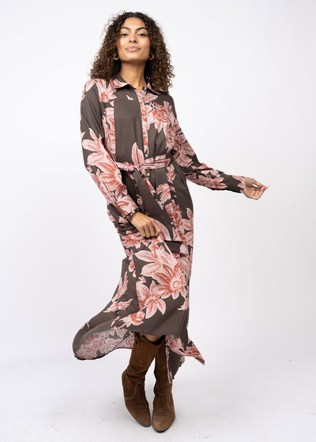 Woman wearing a brown maxi dress with a pink floral print and belt