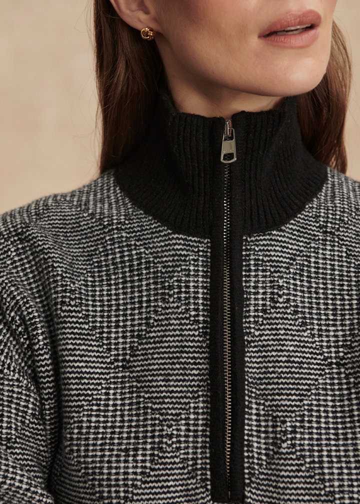 Close up of a woman wearing a black knit half zip top