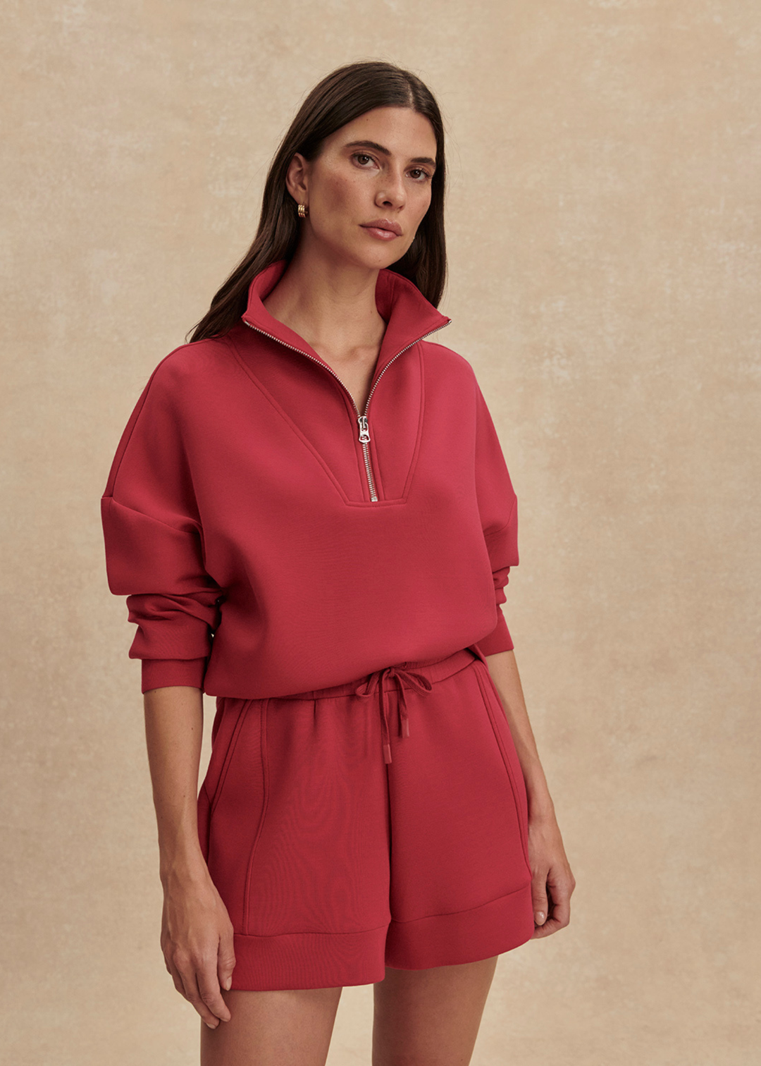 Woman wearing pink shorts and a matching sweatshirt