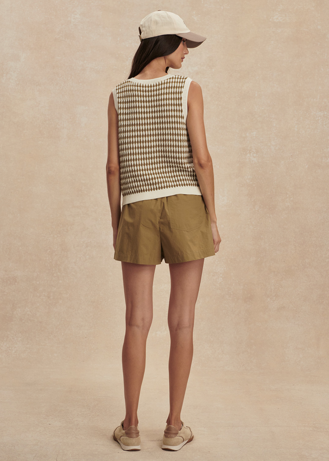 Woman turned around wearing a brown and white knit button up tank top with matching brown shorts