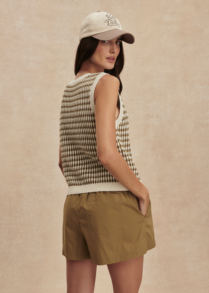 Woman wearing a brown and white knit button up tank top with matching brown shorts