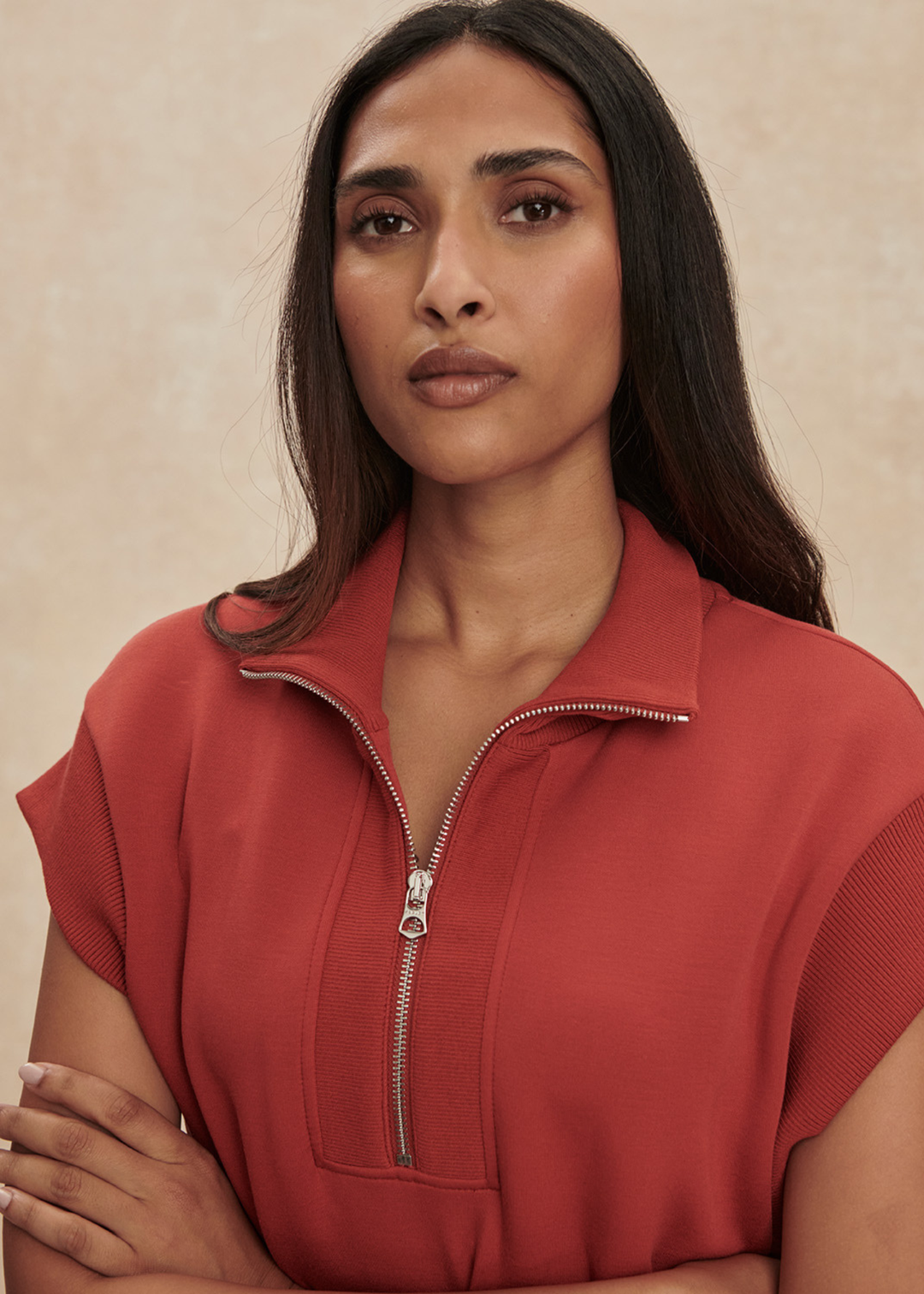 Close up of a woman wearing a red/orange half zip mini dress